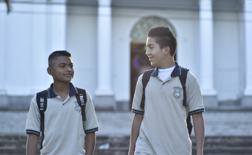 Dos muchachos de colegio, con uniforme y salveque. 
